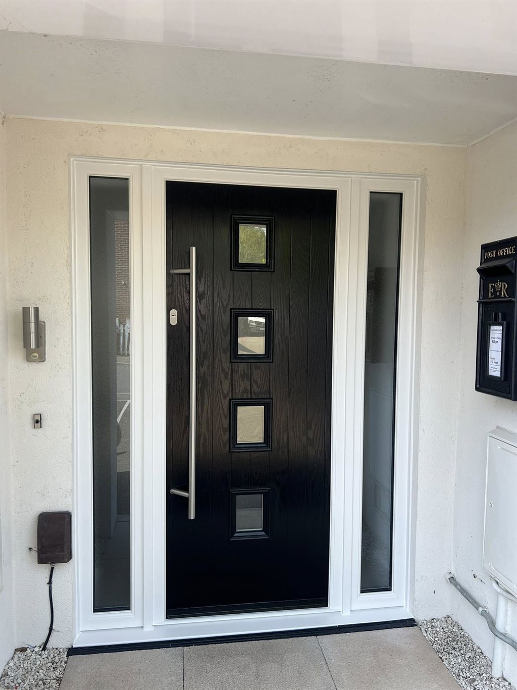 Black composite front door with chrome bar handle and glazed sidelights